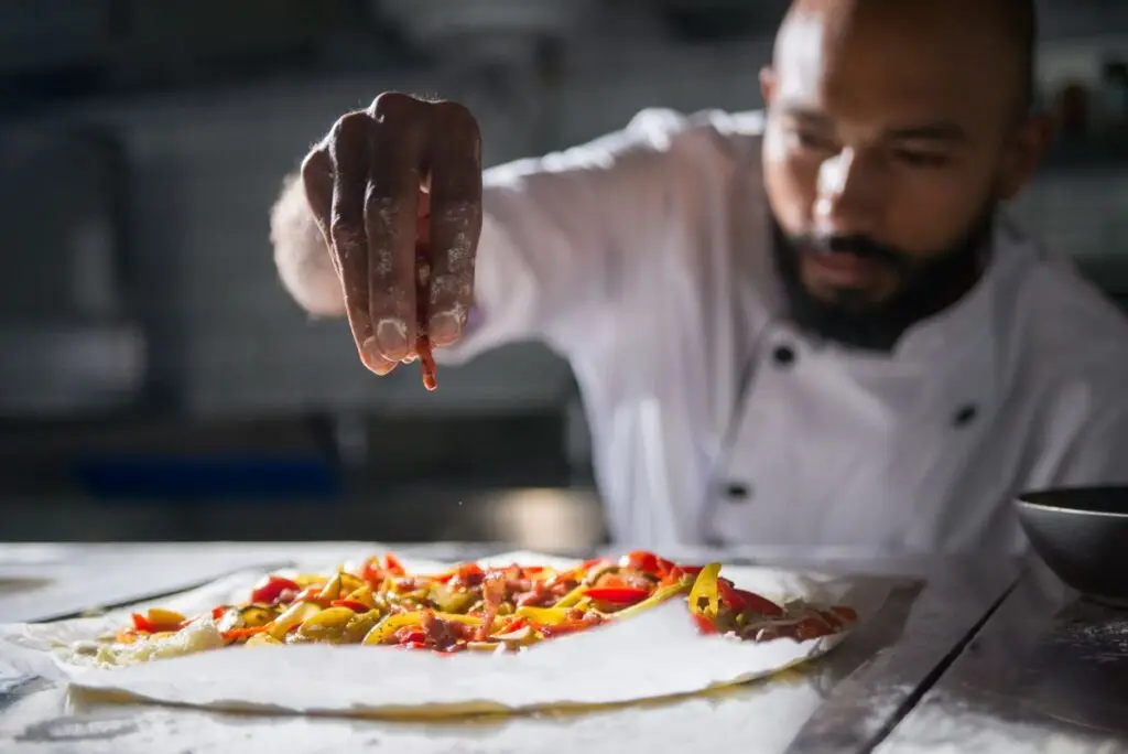 A professional chef preparing a vibrant, fresh plant-based culinary dish.