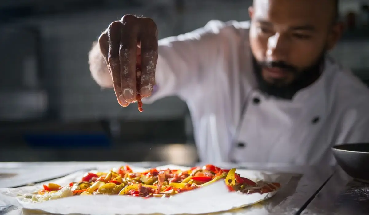 A professional chef preparing a vibrant, fresh plant-based culinary dish.